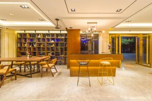 A modern interior with a long dining table, bar stools, and a bookshelf filled with decorative items. - Guilin Tianqing City Hotel (Guilin)