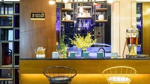 A reception area with a wooden counter, a tea kettle, a vase with flowers, and two chairs.