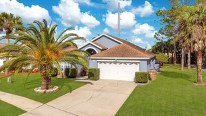 A single-story house with a garage, surrounded by well-maintained lawns and palm trees. - *Tinkerbells Castle 2*  Private Pool & Spa Overlooking Lake & Disney Fire Works (kissimmee)