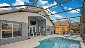 A covered swimming pool area with a ceiling structure, a patio with chairs, and a view of neighboring buildings. - *Tinkerbells Castle 2*  Private Pool & Spa Overlooking Lake & Disney Fire Works (kissimmee)