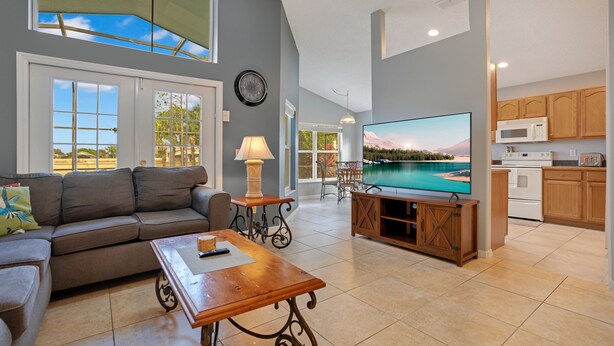A spacious living area with a large flat-screen TV, a sofa, and a wooden coffee table. - *Tinkerbells Castle 2*  Private Pool & Spa Overlooking Lake & Disney Fire Works (kissimmee)