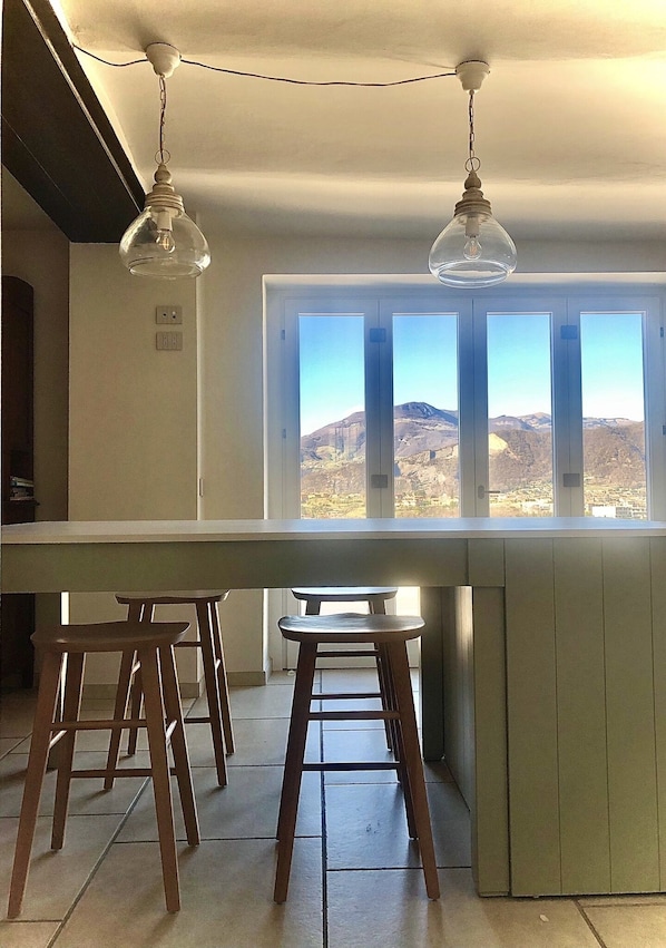 A kitchen with a large window, wooden stools, and a hanging light fixture. - VILLA LE FONTANELLE: lake view, pool, air conditioning, Netflix, wifi, BBQ (paratico)