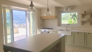 A modern kitchen with a large island, a gas stove, and a window with a view of the outdoors.