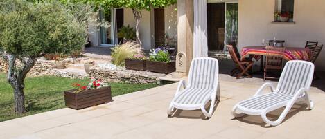 A swimming pool with lounge chairs, a patio area, and a house with a tiled roof.