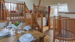 Un espace repas avec des meubles en bois, un escalier et une vue sur le salon.