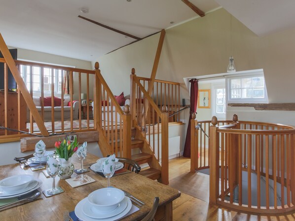 A dining area with wooden furniture, a staircase, and a view of a living room.