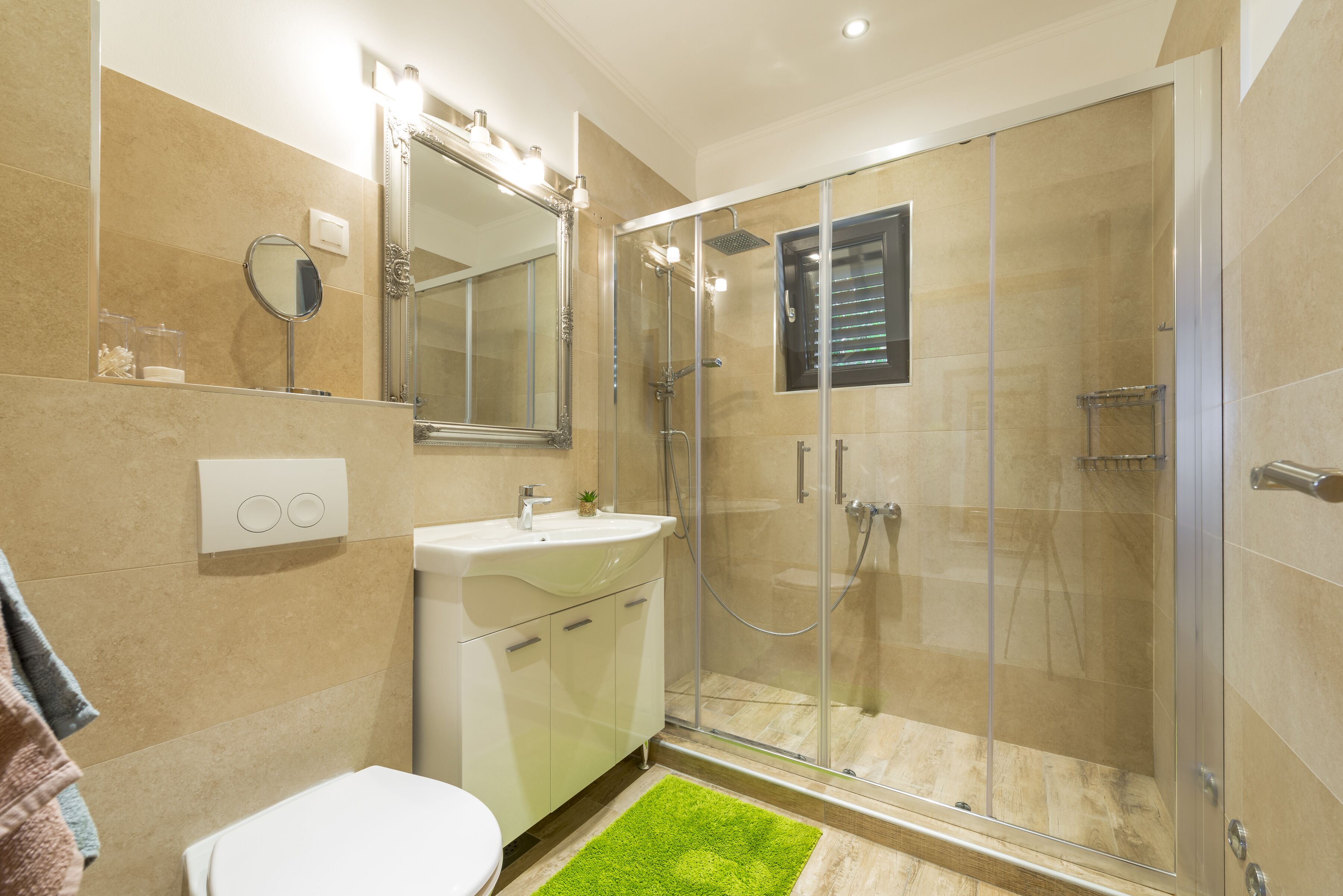A modern bathroom with a glass-enclosed shower, a white sink, and a large mirror.