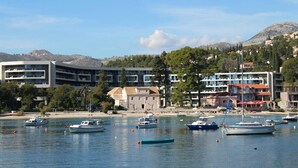 Un pueblo costero con un puerto deportivo, edificios y montañas al fondo.