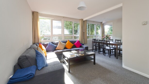 A living room with a sofa, coffee table, and dining area with chairs and a table. - Spacious Notting Hill Flat (London)