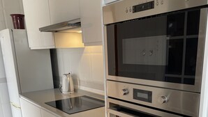 A modern kitchen with white cabinetry, a built-in oven, and a stovetop. - Luxury 2 Bedroom Bungalow With Communal Pool & Wifi On Golf Resort (Antigua)