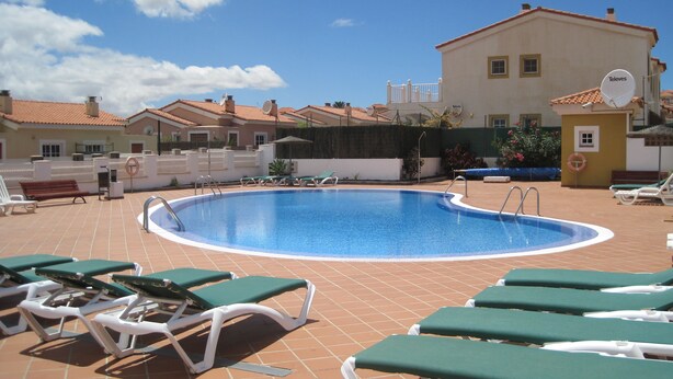 A swimming pool with lounge chairs and a building in the background. - Luxury 2 Bedroom Bungalow With Communal Pool & Wifi On Golf Resort (Antigua)
