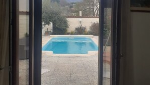 Blick durch eine Schiebetür auf einen Swimmingpool mit Bergblick.