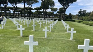 Ein Friedhof mit zahlreichen weißen Kreuzen, die in Reihen auf einer gepflegten Rasenfläche angeordnet sind.