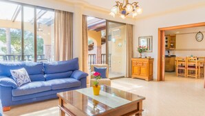 A living room with a blue sofa, a glass coffee table, and a view of the outdoor area. - Apartamento cerca de la playa Can Berenguer (Port d´Alcudia)