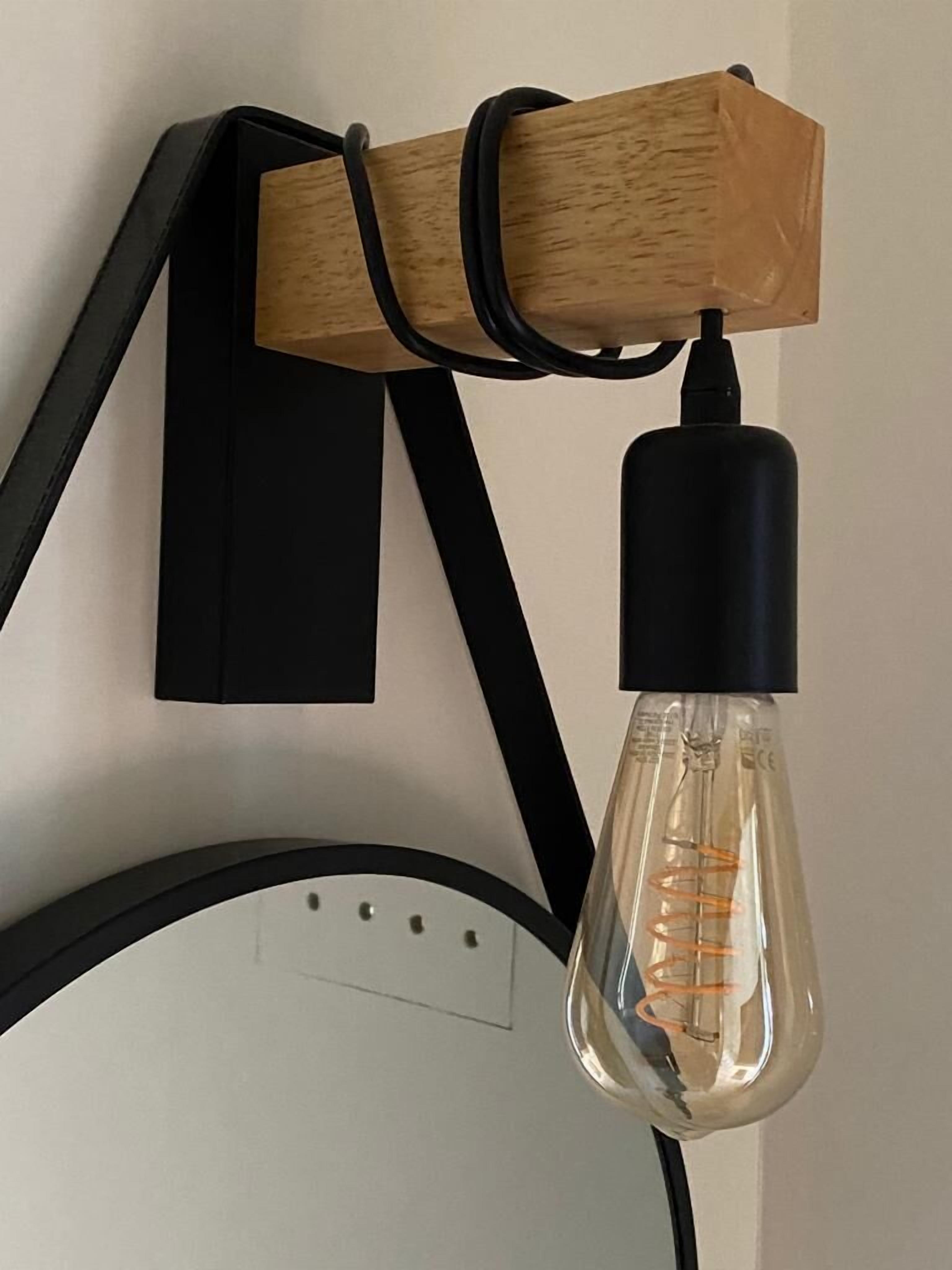 A light fixture with a clear glass bulb and a wooden base.