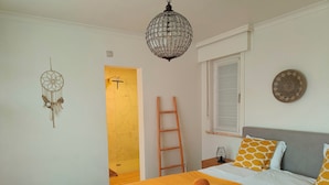 Une chambre à coucher bien rangée, avec un lit, un attrape-rêves, une échelle et un luminaire suspendu.