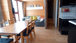 A wooden interior with a dining table, chairs, a sofa, and a kitchen area. - Apartment/ flat - LES ARCS 2000 (Bourg-Saint-Maurice)