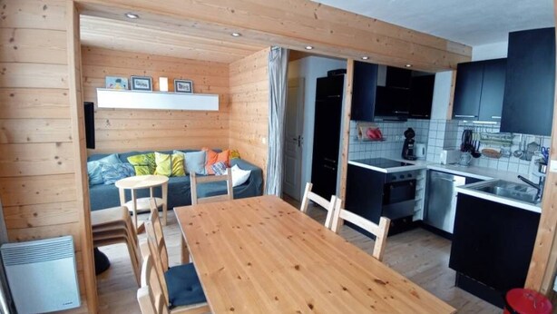 A compact kitchen with modern appliances, a dining area with a wooden table and chairs, and a cozy seating area with cushions. - Apartment/ flat - LES ARCS 2000 (Bourg-Saint-Maurice)