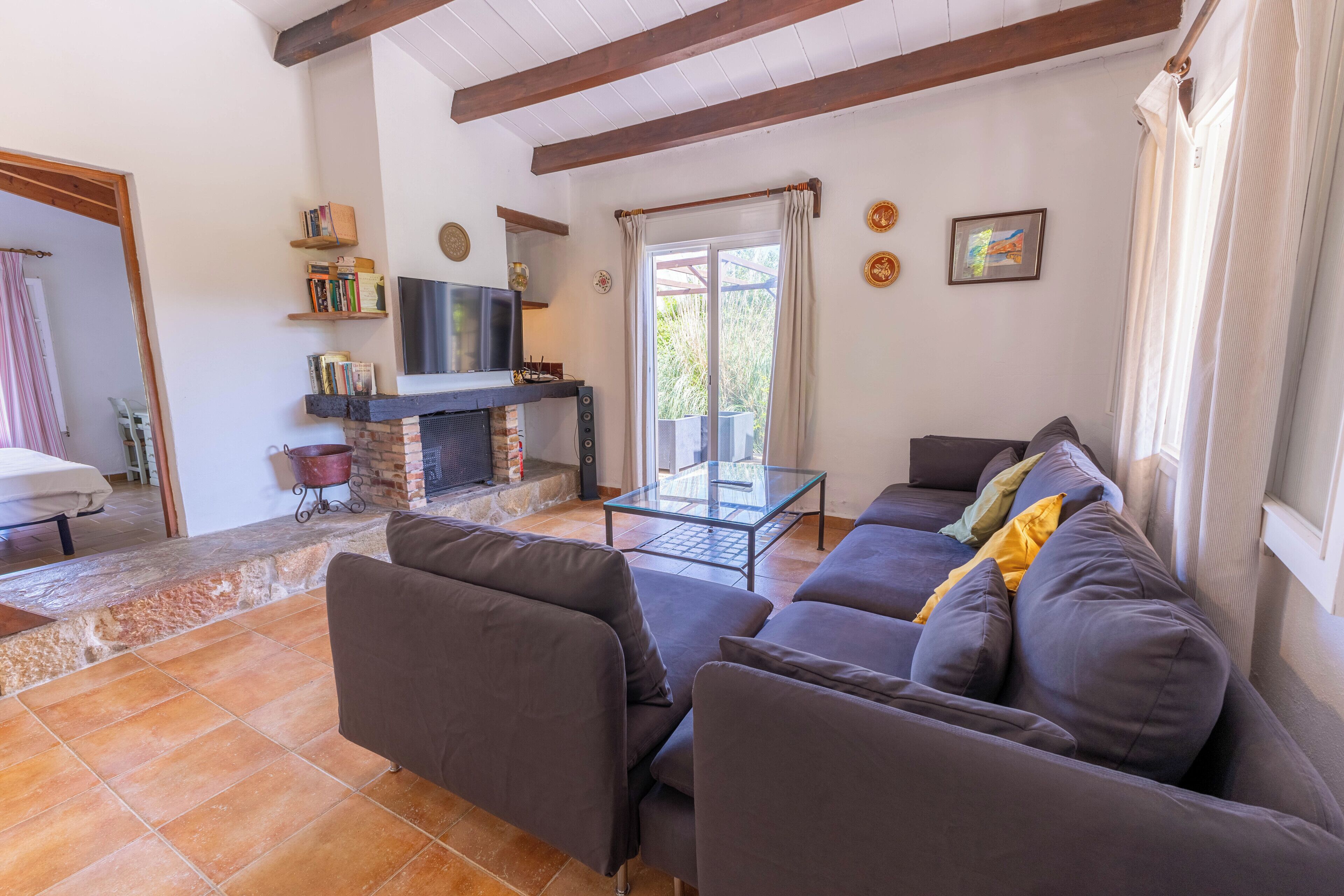 A living room with a sofa set, a fireplace, a television, and a glass table.