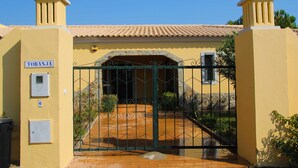 A yellow building with a sign reading "TORANJA" and a gated entrance with a tiled roof.