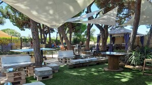 An outdoor patio area with seating arrangements, a table, and a pergola providing shade.