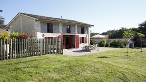 Une maison à deux étages avec une façade en pierre, une clôture en bois et une allée gravillonnée.