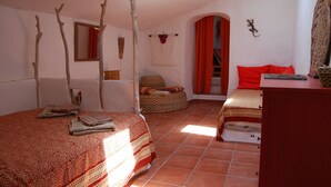 Quarto com duas camas, colcha estampada em vermelho e branco, travesseiro vermelho, cadeira de fibra e luminária em formato de estrela.