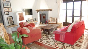 Uma sala de estar com sofás vermelhos, lareira e chão ladrilhado.