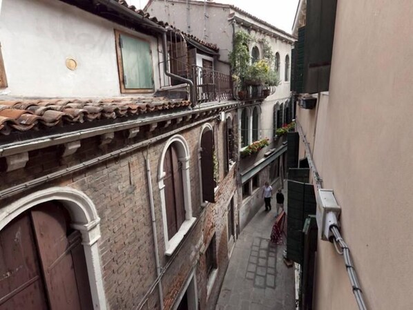 A narrow alleyway with traditional architecture, including arched windows and a tiled roof.