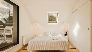 A bedroom with a bed, a small window, and a view of the outdoors. -  In a green setting close to the ocean  (Saint-Molf)