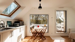 A modern kitchen with a skylight, a dining area with a table and chairs, and a large sliding glass door leading to an outdoor patio. -  In a green setting close to the ocean  (Saint-Molf)
