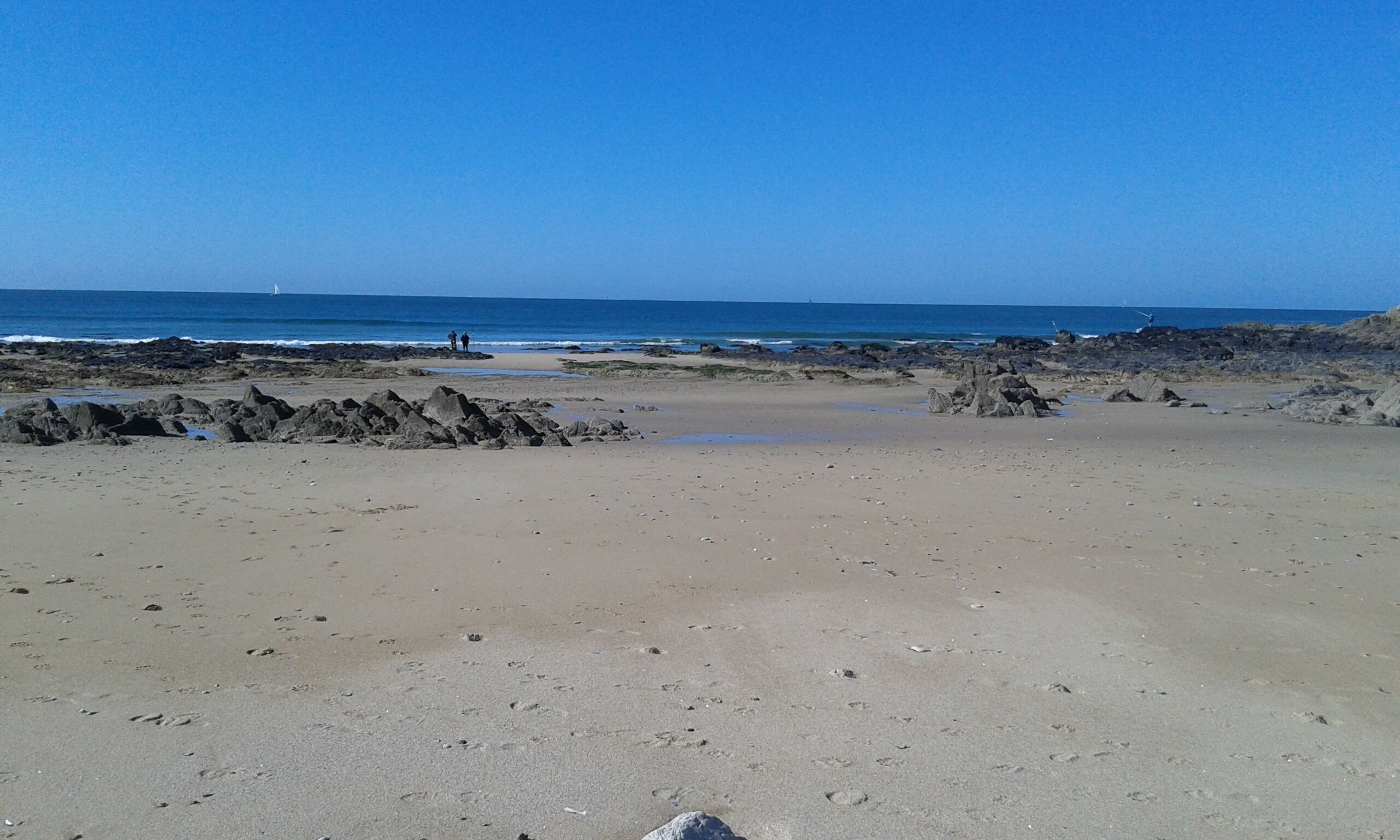 Una playa con terreno rocoso y una vista despejada del océano.