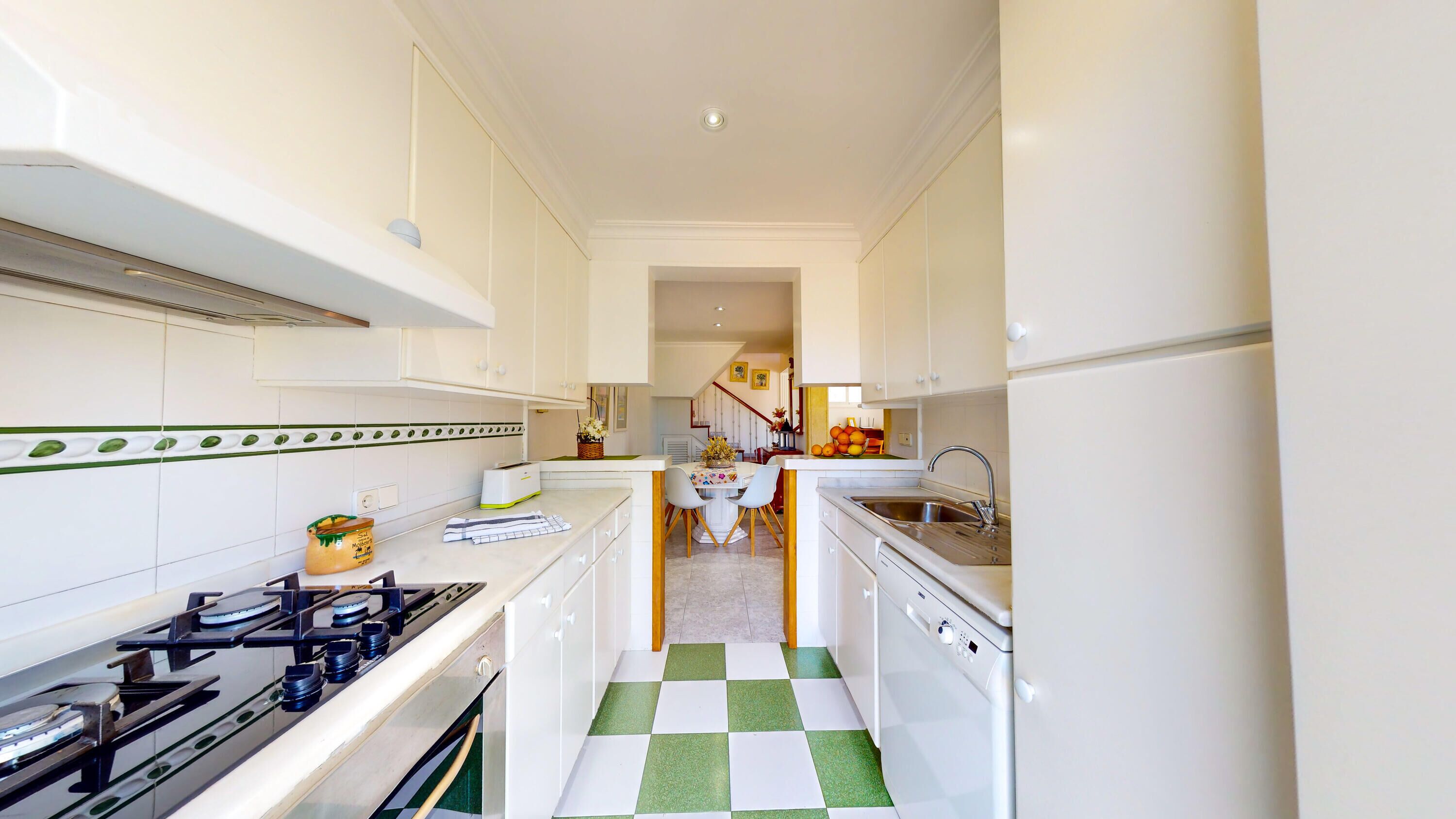 A modern kitchen with white cabinets, a gas stove, a dishwasher, and a checkered floor.