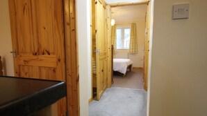 En smal hall som leder till ett sovrum med en säng och ett fönster.