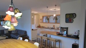 A modern kitchen with a wooden island, pendant lights, and a dining area with a round table and bar stools.