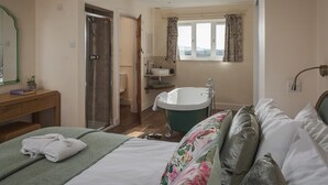 A hotel room with a bed, a green bath tub, a shower, and a window with curtains. - Apple Cottage - sleeps 4 guests  in 0 bedrooms (Shepton Mallet)