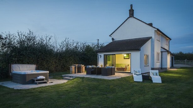 A modern house with a patio area featuring outdoor seating and a hot tub. - Apple Cottage - sleeps 4 guests  in 0 bedrooms (Shepton Mallet)