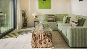 A modern living room with a green sofa, a glass coffee table, and a green pendant light. - Apple Cottage - sleeps 4 guests  in 0 bedrooms (Shepton Mallet)
