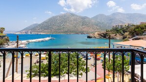 A coastal view with a mountain in the background, a pier, and a beach area with umbrellas and chairs. - Sea-esta Beach House, Beachfront Residence & BBQ (Rethymno)