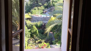 Vista de uma varanda com um muro de pedra, piscina e vegetação ao redor.