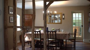 Un comedor con una mesa dispuesta para cuatro personas, rodeada de sillas de madera, un candelabro y un espejo en la pared.