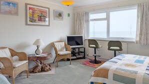 Una camera d'albergo con un letto, due poltrone, una televisione, una lampada e opere d'arte alle pareti.