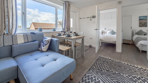 A modern, well-lit room with a sofa, a dining table, and a bed.