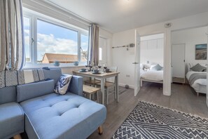 Et moderne, lyst værelse med sofa, spisebord og seng.