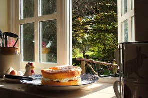 Enjoy a homey atmosphere in this kitchen with a garden view, complete with a stove and kettle.