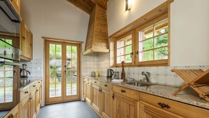A kitchen with wooden cabinets, a granite countertop, and a window with a view of greenery. - Chalet Jessica - La Tzoumaz, 4 Vallees (La Tzoumaz)