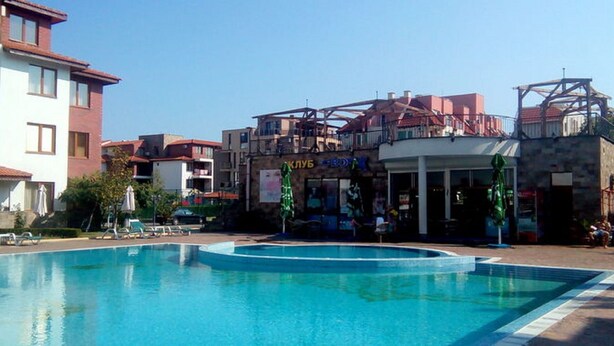 Une piscine entourée de bâtiments, dont un restaurant et un bar.