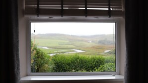 A room with a large window overlooking a green landscape. - Traditional Croft Cottage Overlooking The Snizort River - Portree, Isle Of Skye (Portree)