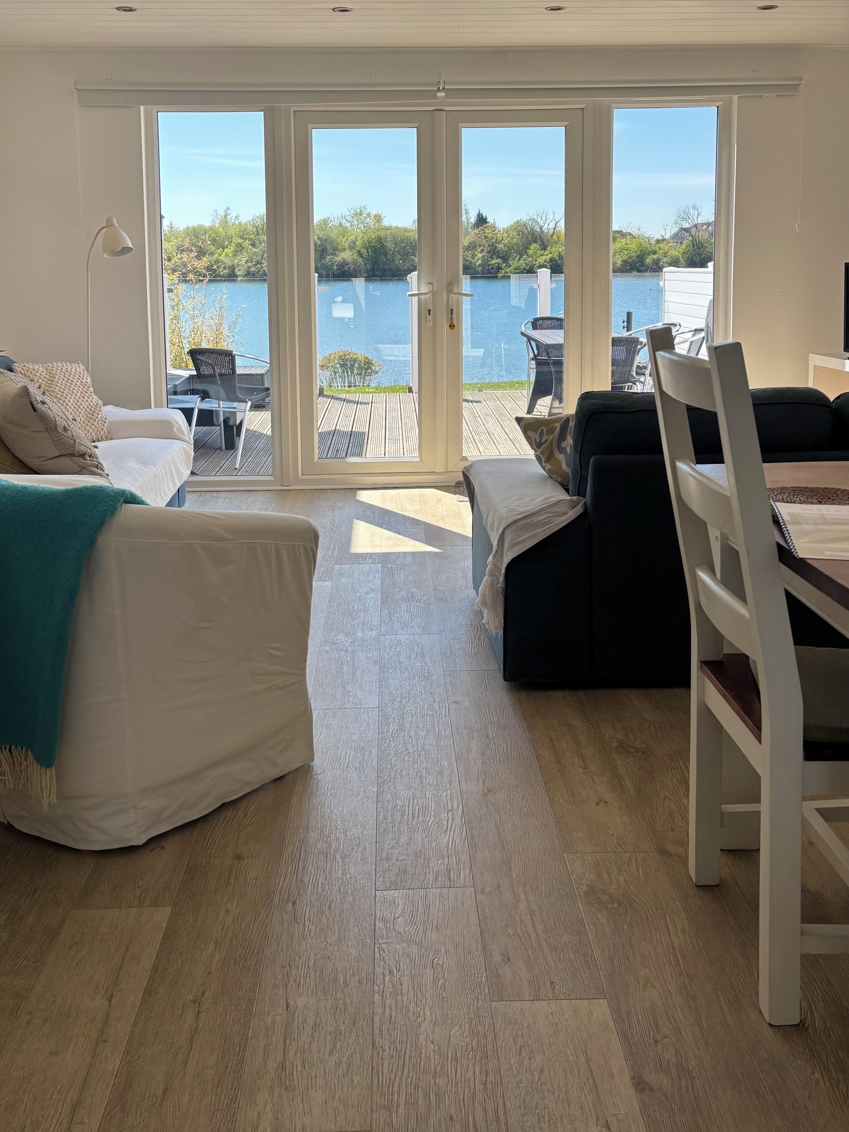 Un vaste espace de vie comprenant une grande porte-fenêtre coulissante donnant sur une terrasse extérieure, un canapé, une table à manger et une chaise.
