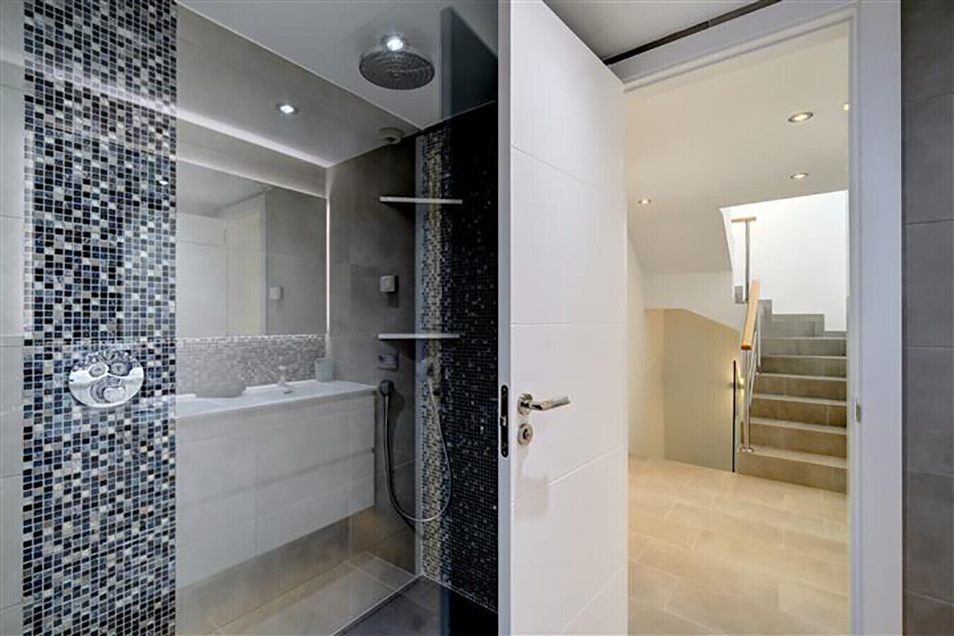 A modern bathroom with a mosaic tile wall, a bathtub, and a shower.